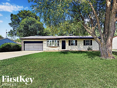 a small white house with a yard and a tree