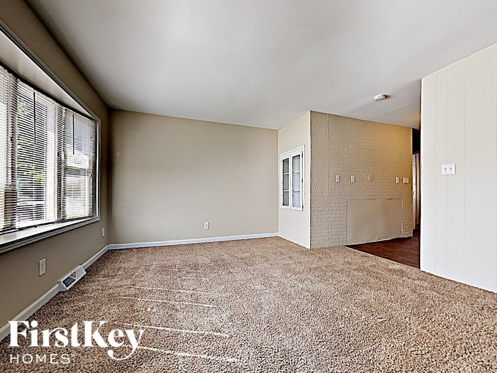 an empty living room with a large window and carpeting