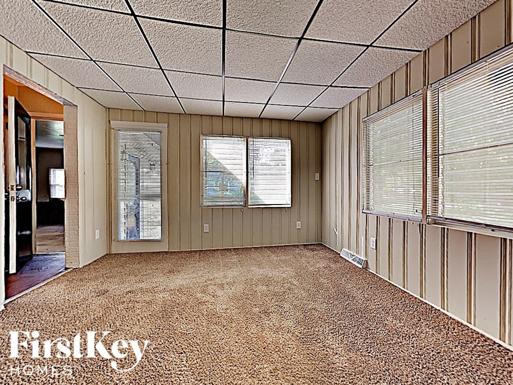 an empty room with a carpeted floor and three windows