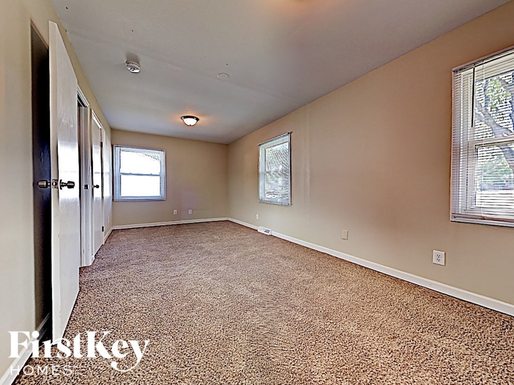 an empty living room with carpet and a window