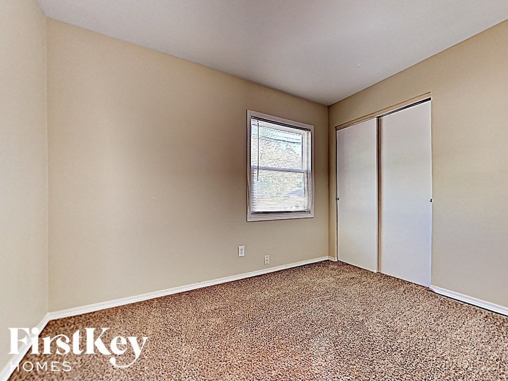an empty bedroom with a closet and a window