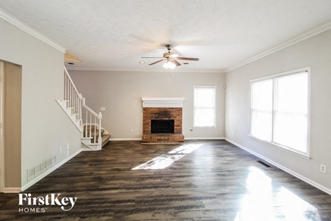 an empty living room with a fireplace and a ceiling fan