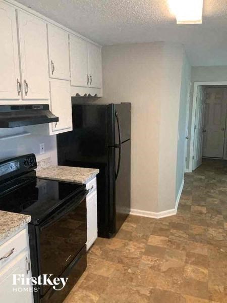 A kitchen with black appliances and white cabinets.