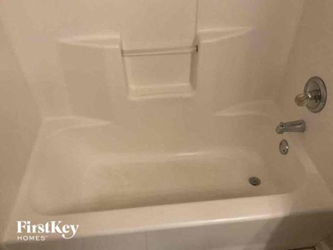A white bathtub with a faucet and a shower head.