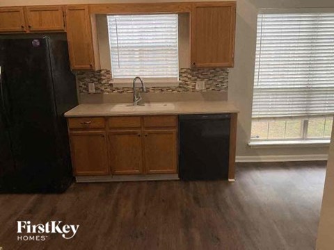 A kitchen with wooden cabinets and a black refrigerator.