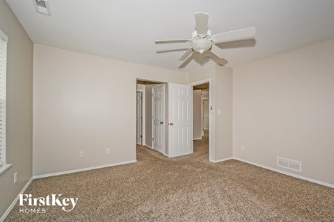 a spacious living room with carpet and a ceiling fan