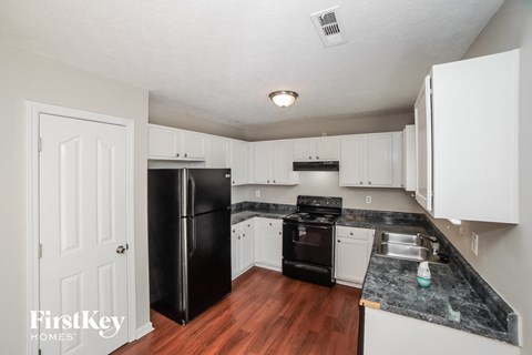 a kitchen with white cabinets and black appliances