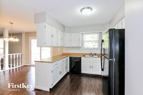 A kitchen with white cabinets and a black fridge.