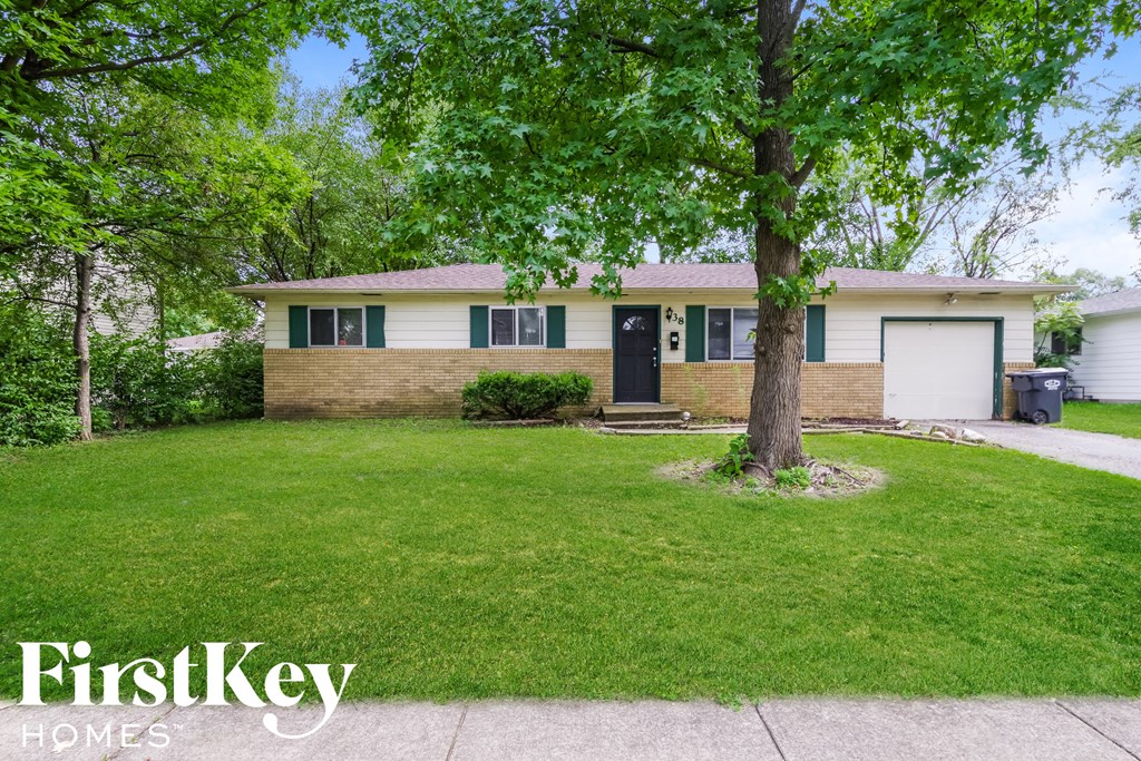 A house with a lawn and a tree in front of it.