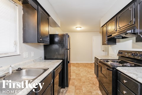 A kitchen with black cabinets and a tiled floor.
