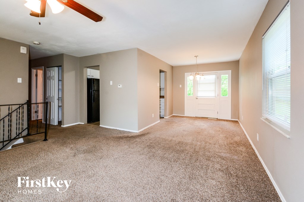 an empty living room with a ceiling fan and a window