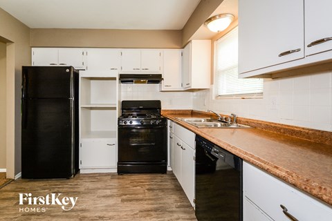a kitchen with white cabinets and black appliances and a counter top