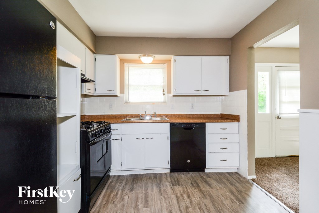 an empty kitchen with white cabinets and black appliances