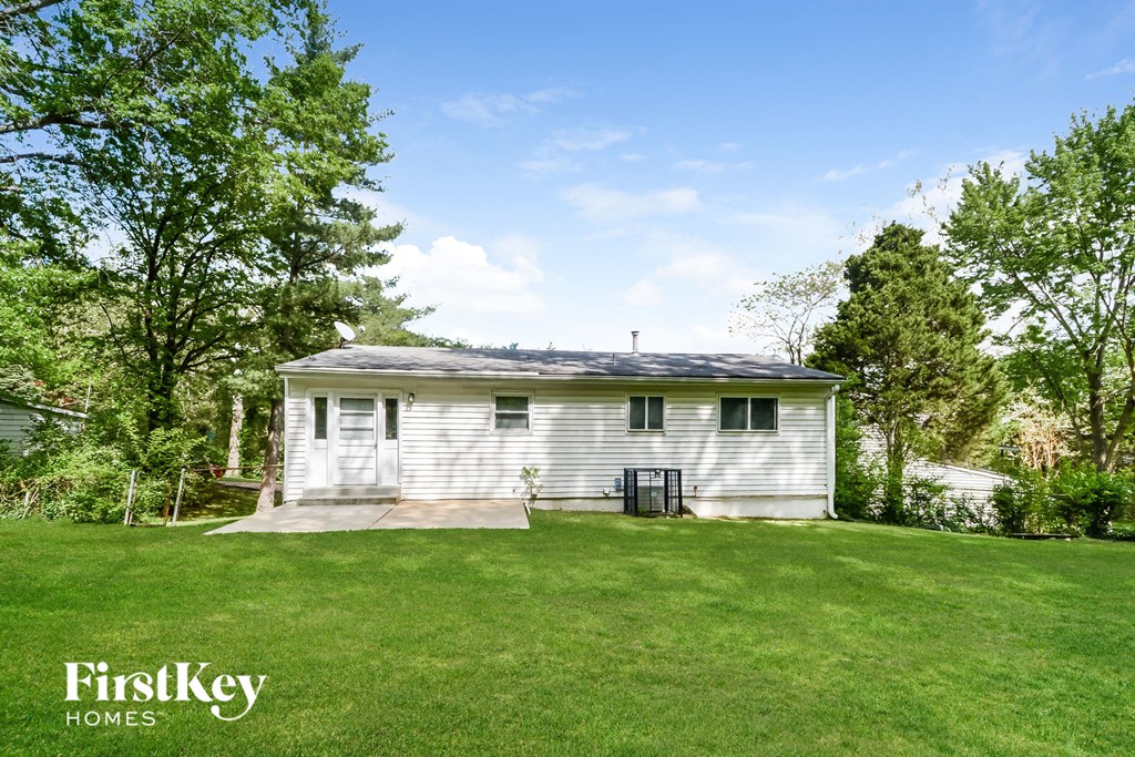 a small white house in the middle of a grassy yard