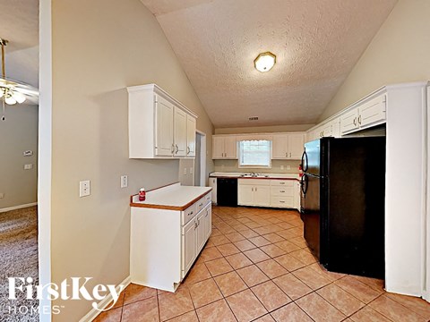 A kitchen with white cabinets and a black refrigerator.