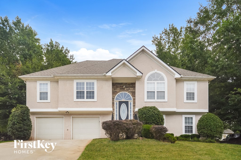 a beige house with white doors and a lawn