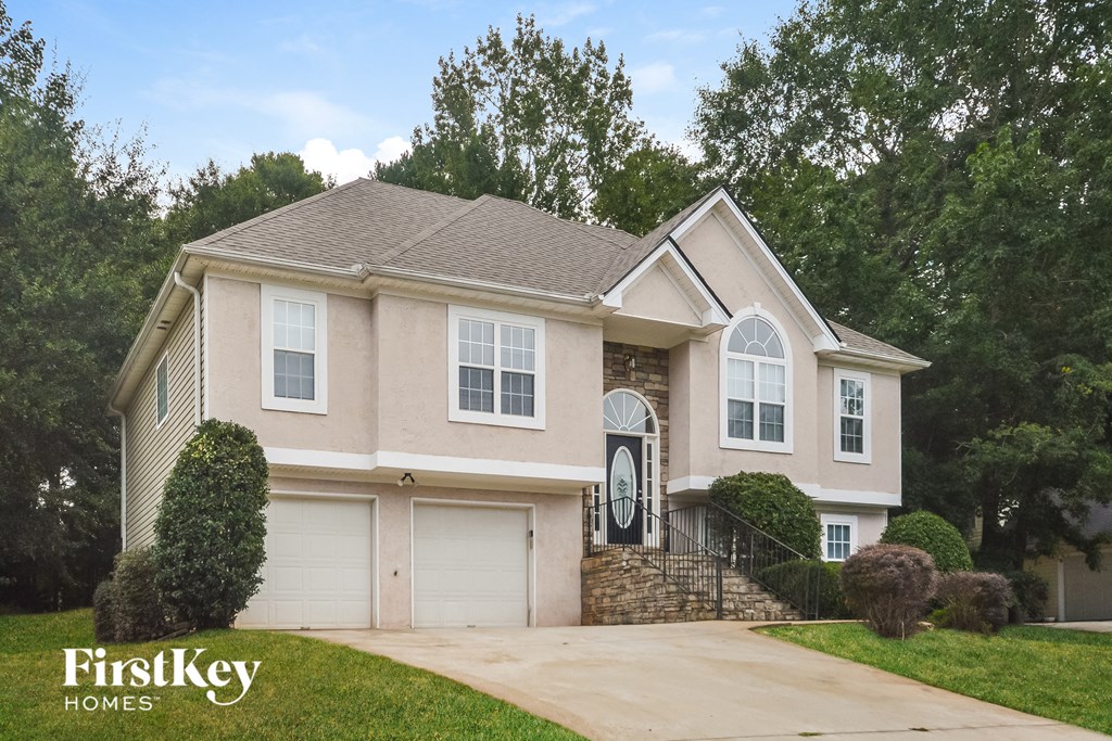 a beige house with white doors and a driveway