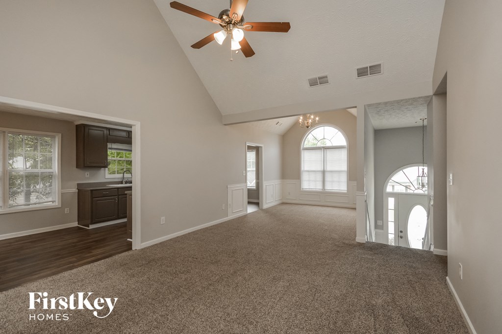an empty living room with a ceiling fan