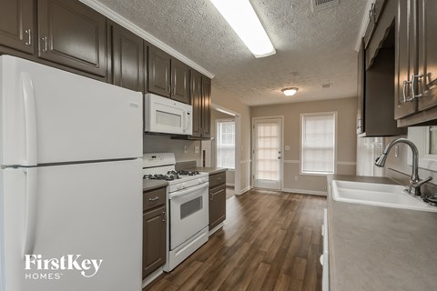 a kitchen with white appliances and wood flooring and a white refrigerator
