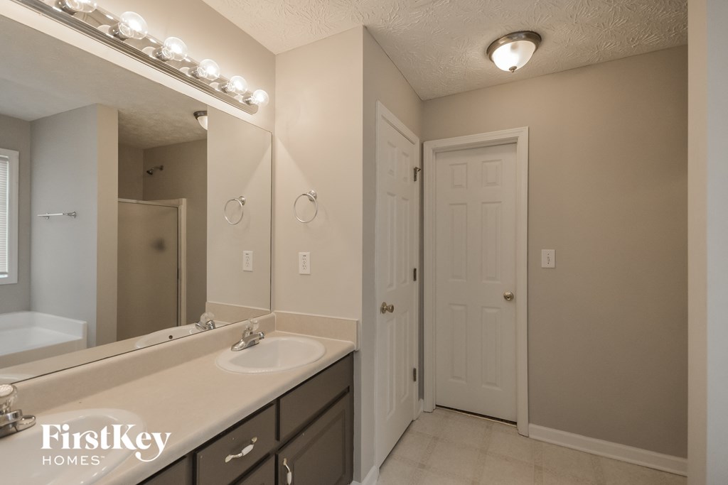a bathroom with a sink and a mirror and a door to the shower