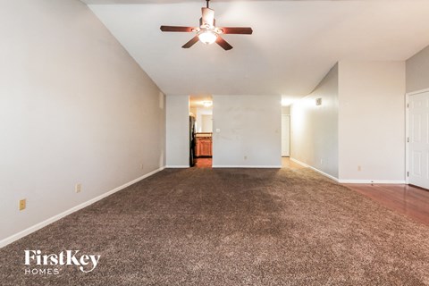A spacious room with a ceiling fan and carpeted floor.