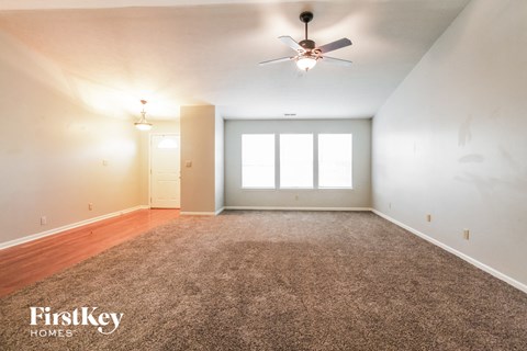 A spacious room with a carpeted floor and a ceiling fan.