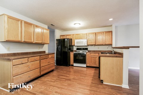 A kitchen with wooden cabinets and a black refrigerator.