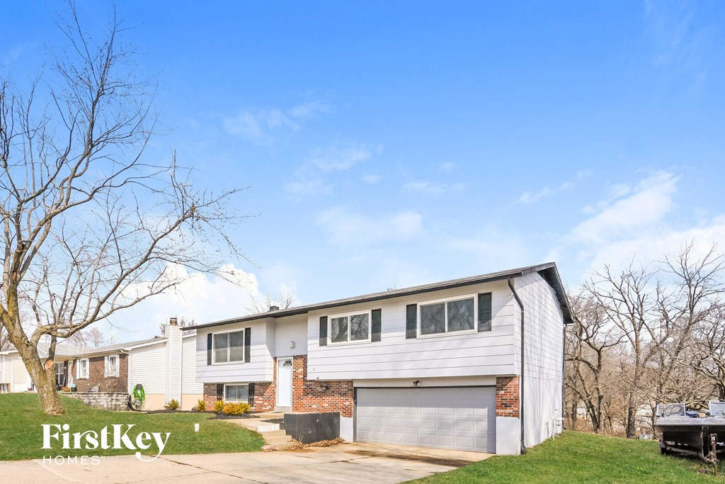 a white and brick house with a garage and a blue sky