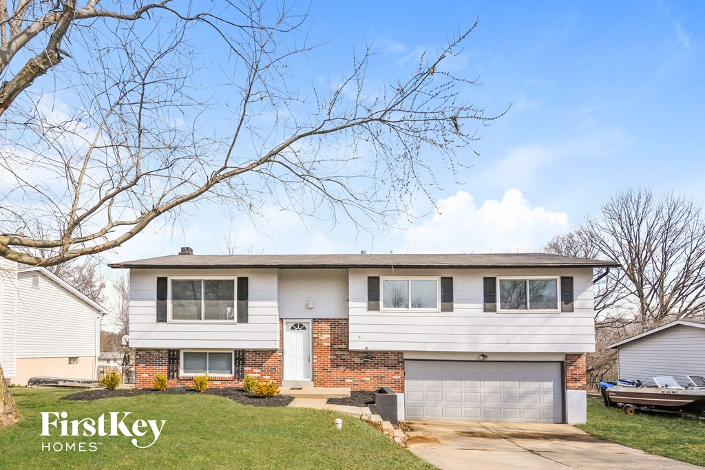 a white and brick house with a yard and a tree
