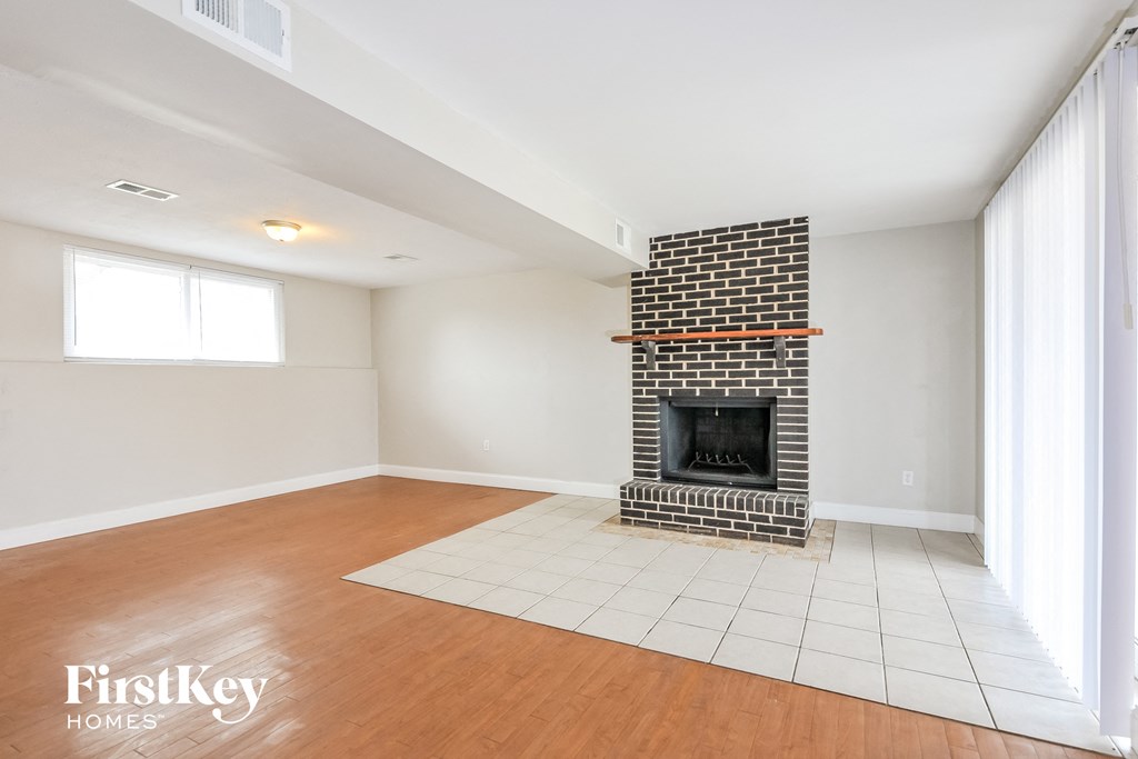 a living room with a brick fireplace and wooden floors