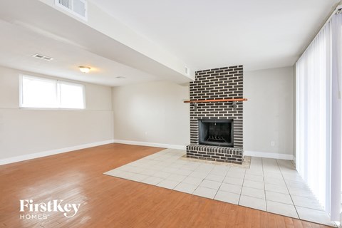 a living room with a brick fireplace and wooden floors