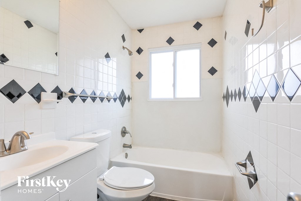 a white bathroom with black and white tiles and a window