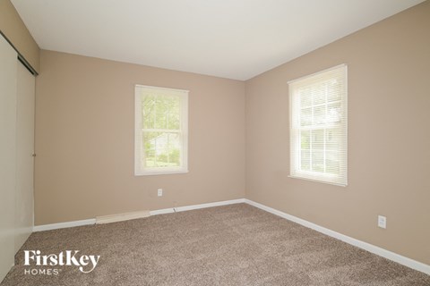 the bedroom of a home with carpet and two windows