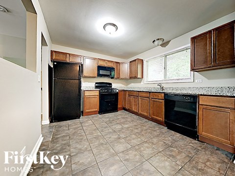 A kitchen with a black refrigerator and black oven with brown cabinets.