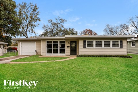 the front of a house with a lawn and a driveway