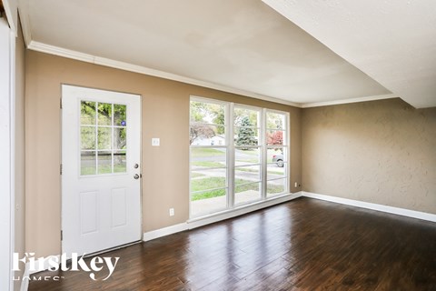 the living room of a home with wood floors and a white door