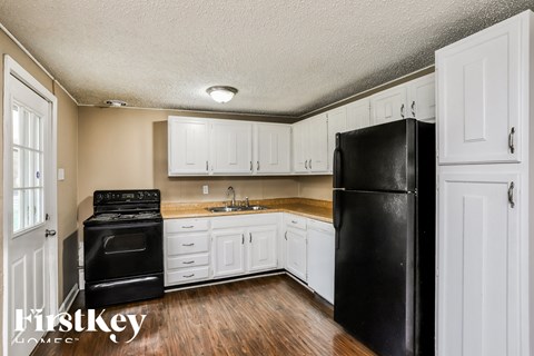 a kitchen with white cabinets and a black refrigerator