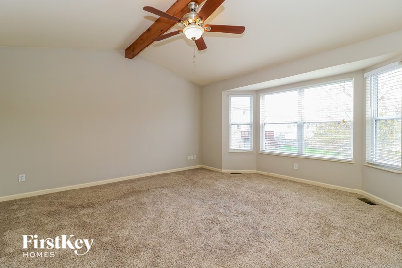 A spacious room with a ceiling fan and carpeted floor.