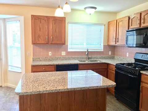 A kitchen with wooden cabinets and granite countertops.