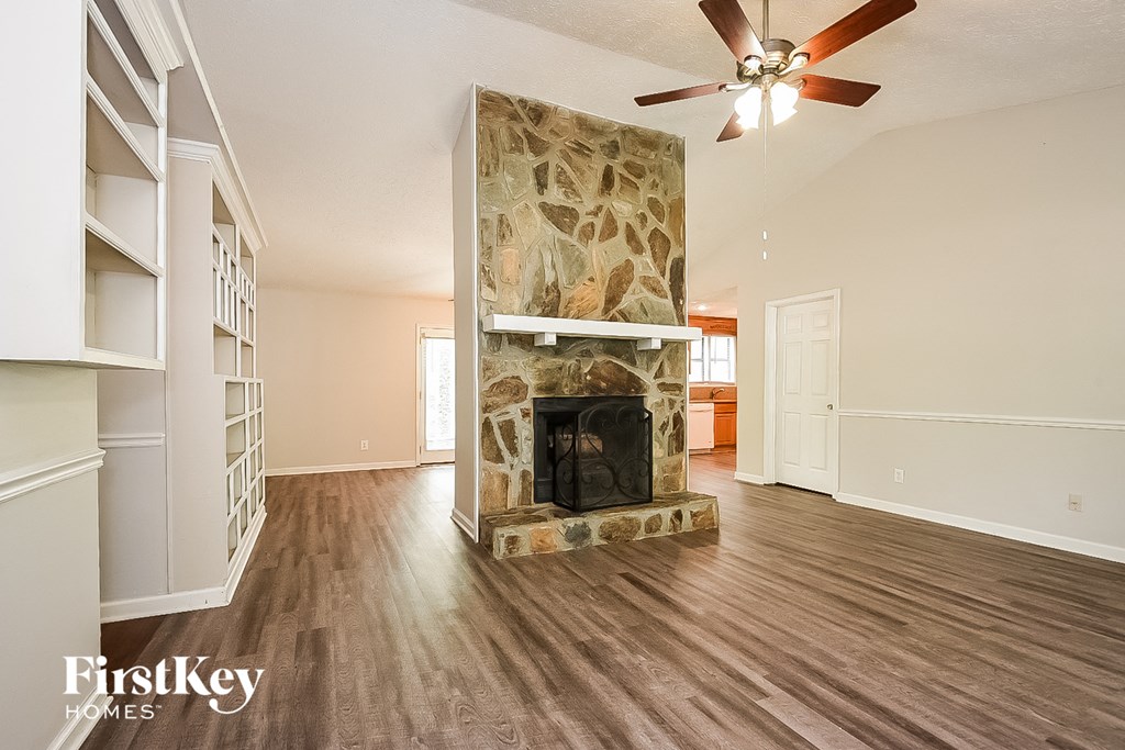 A spacious living room with a stone fireplace and wood flooring.