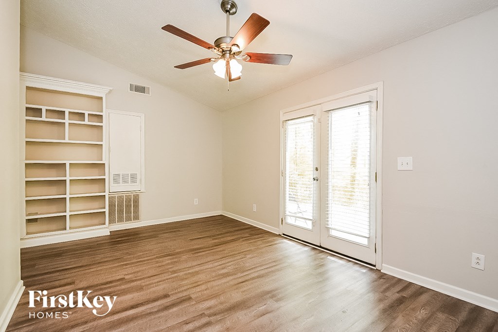 A room with a ceiling fan and wooden flooring.