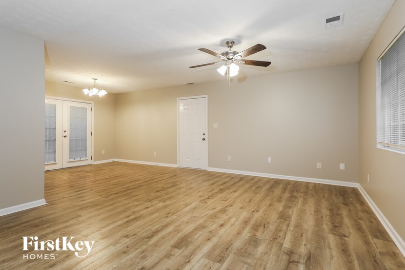 A spacious room with wooden flooring and a ceiling fan.