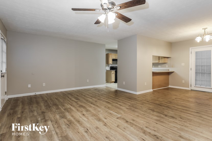 A spacious room with wooden flooring and a ceiling fan.
