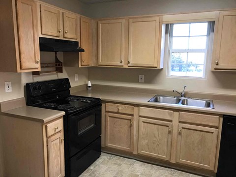A kitchen with wooden cabinets and a black stove top oven.