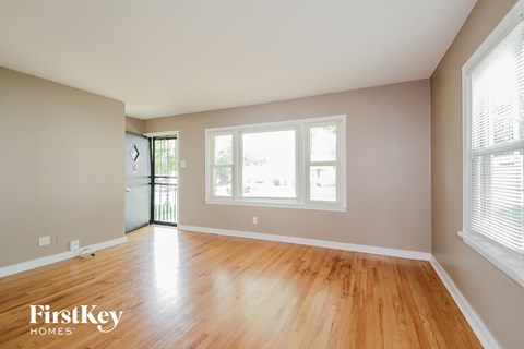 A room with wooden floors and a window with blinds.
