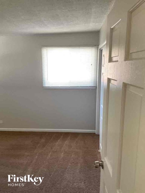 A room with a door and a window with blinds.