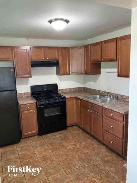 A kitchen with brown cabinets and black appliances.