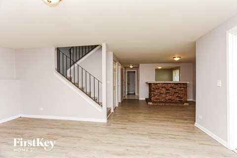 A spacious living room with a staircase and a fireplace.