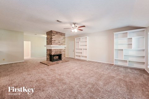 A living room with a fireplace and a ceiling fan.