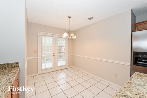 A kitchen with a granite counter top and a tile floor.